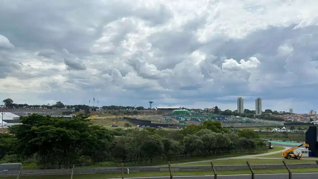 F1 luxury vacation package  Interlagos circuit and tree-lined infield beneath dramatic clouds, with grandstands in the distance.