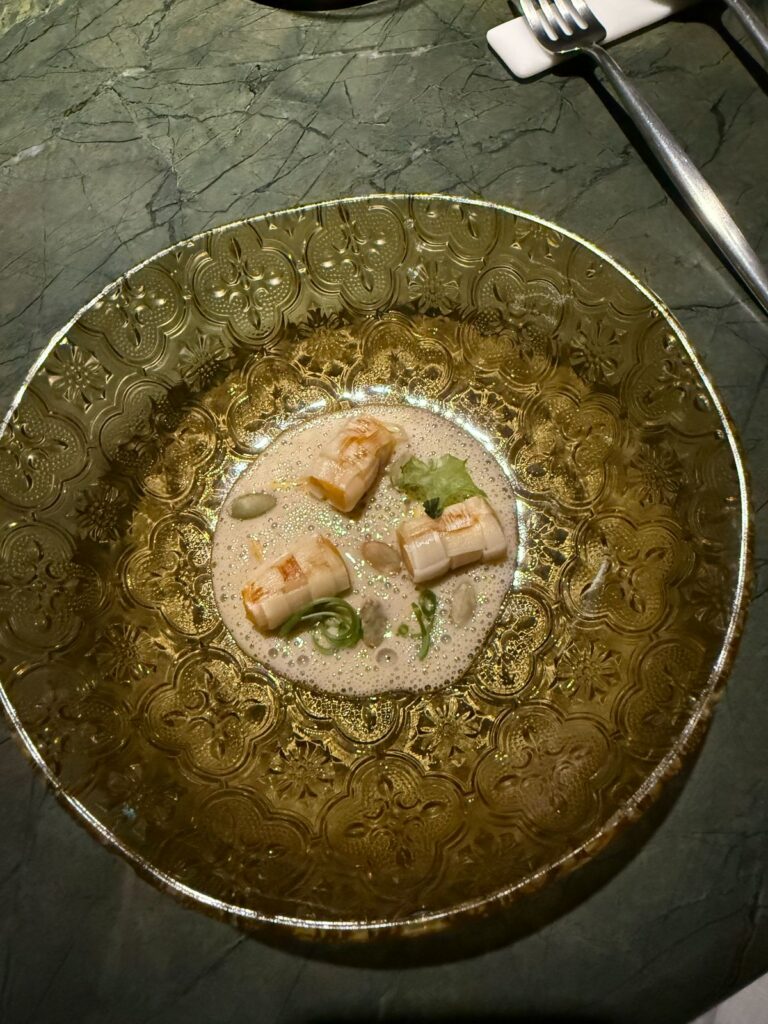 A plated course in a textured green glass bowl on a green marble table at Tuju.