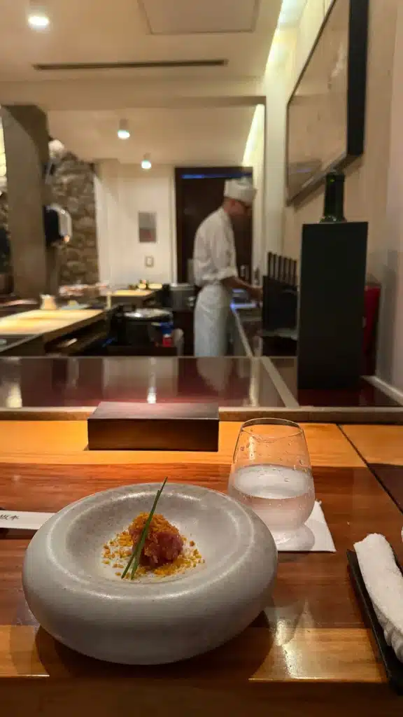 Saying Yes A plated dish at the Jun Sakamoto counter, with a chef working behind it.
