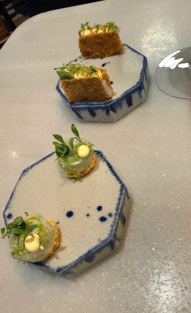 Small plated courses with green garnishes on blue-edged ceramic dishes at Mont Bar.