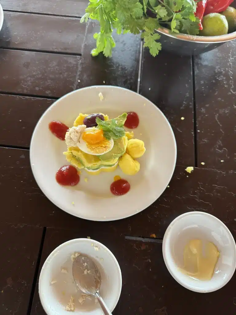 Saying Yes A layered dish on a white plate, with small bowls of ingredients on a wooden table.
