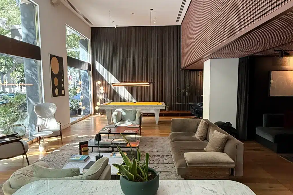 F1 luxury vacation package  Sunlit Sir Victor lobby in Barcelona, with lounge seating, books, plants and a pool table.