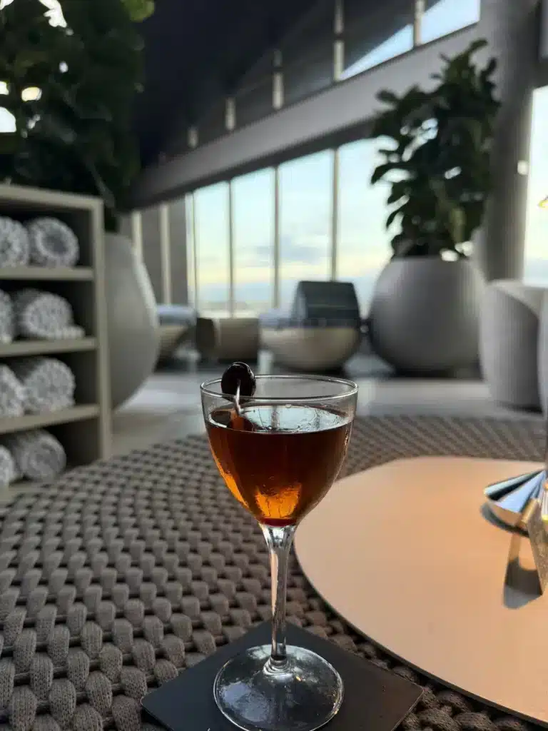 Saying Yes A drink in a stemmed glass on a table beside the windows of a hotel lounge.
