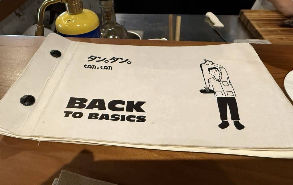 Tan Tan’s Back to Basics menu booklet resting on the wooden bar.