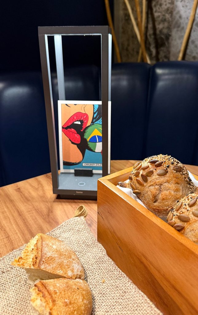 Bread in a wooden box beside an illustrated course card in a metal stand at Evvai.