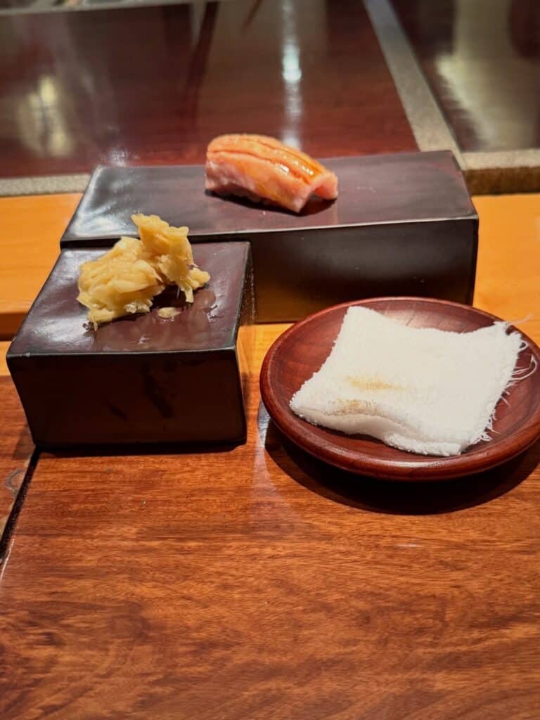 Nigiri on a dark serving block beside pickled ginger at Jun Sakamoto’s sushi counter in São Paulo.