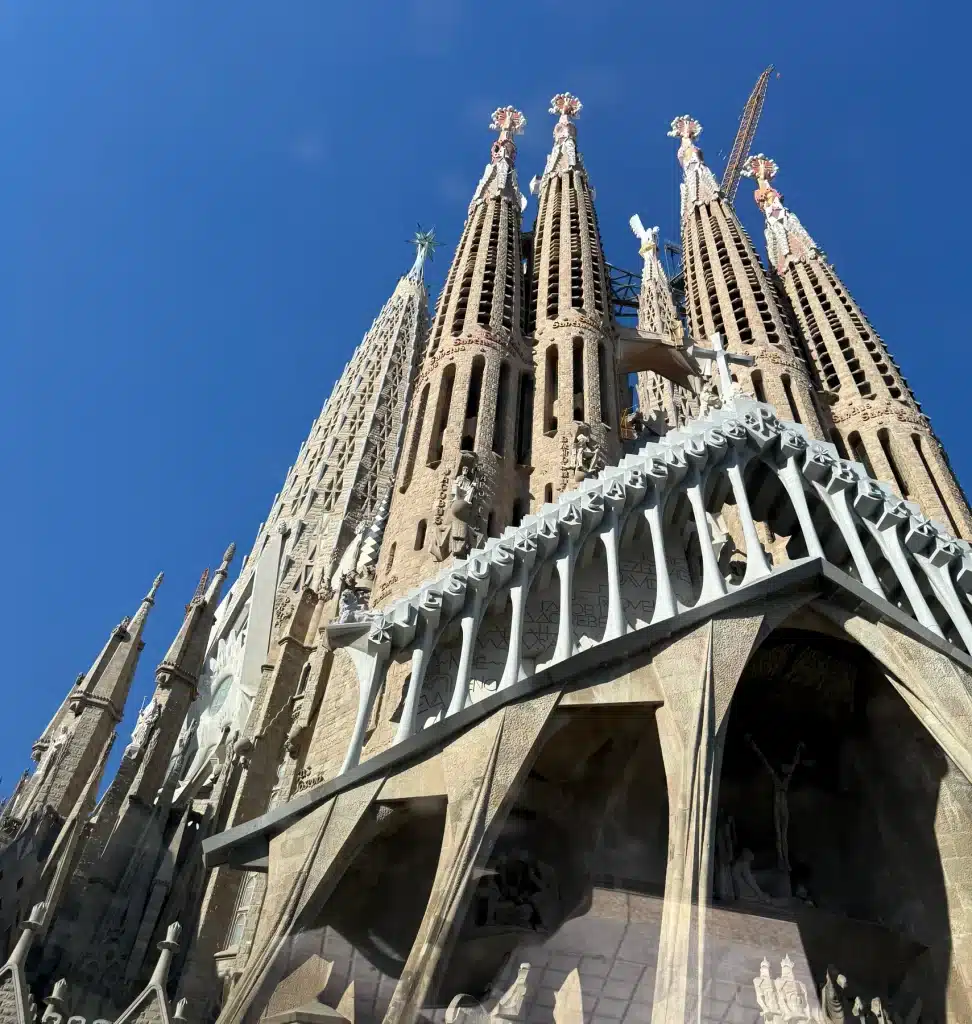 F1 luxury vacation package Towers and stone façade of the Sagrada Família in Barcelona against a clear blue sky.