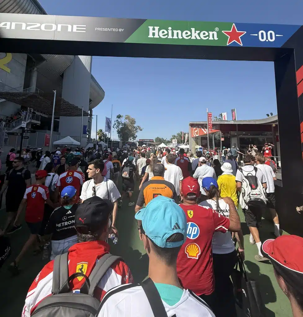 Fans in Ferrari, Mercedes and McLaren clothing walk through the Barcelona Formula 1 fan zone.