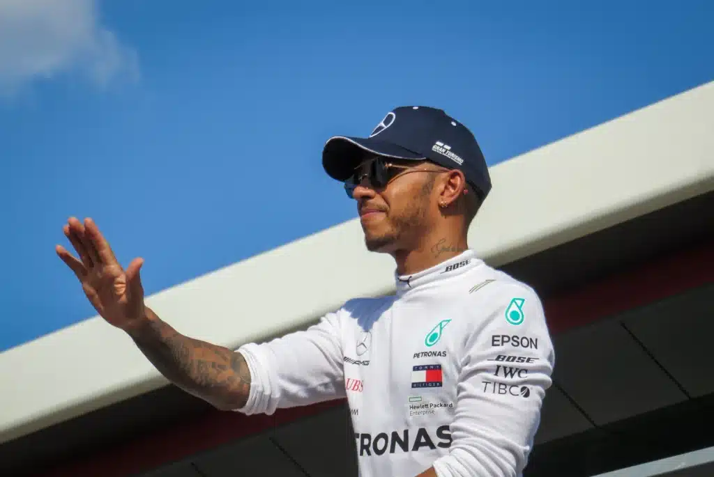 Lewis Hamilton Paintball Story Lewis Hamilton waves in white Mercedes team clothing and a navy cap at Silverstone in 2018.
