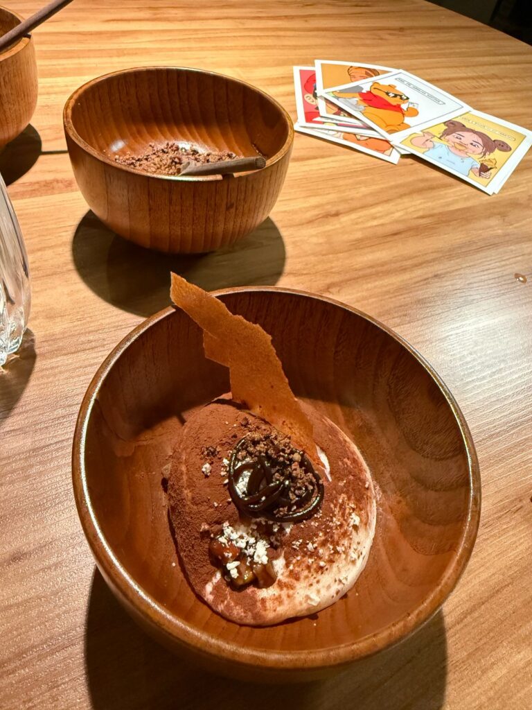 Desserts in wooden bowls with illustrated pop-art cards on the table at Evvai.
