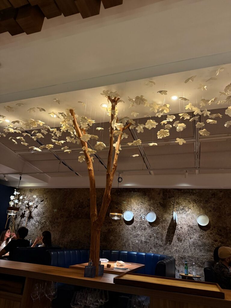 Evvai dining room with sculptural branches, hanging white flowers and blue banquettes.