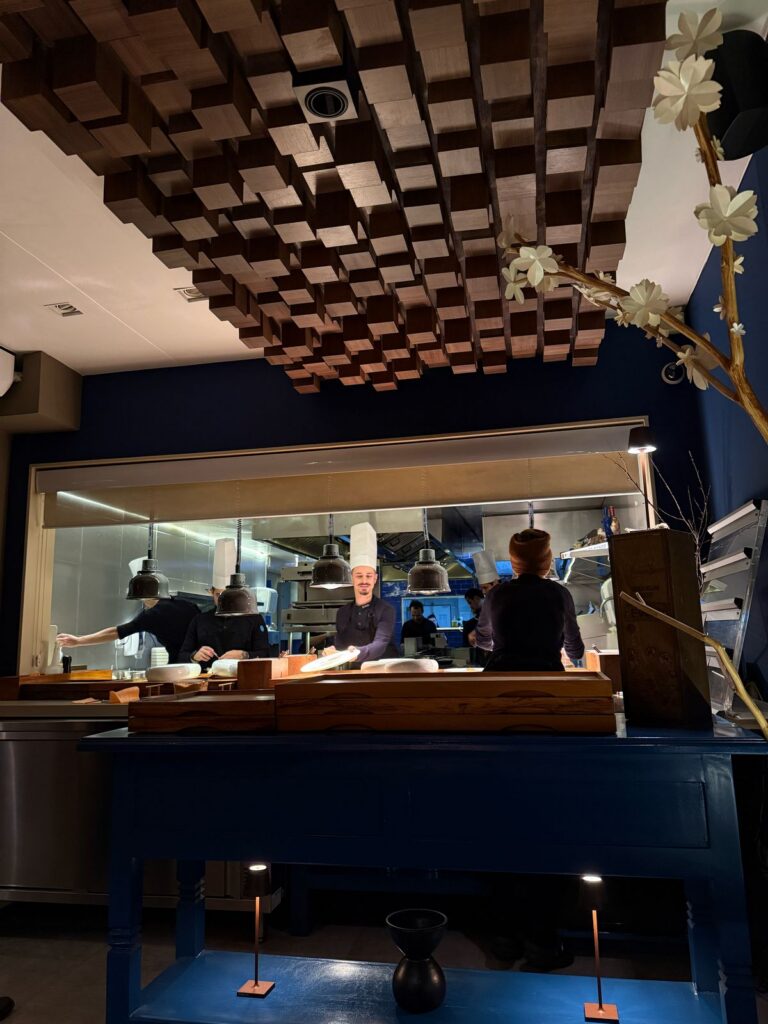 Chefs working in Evvai’s open kitchen beneath a geometric wooden ceiling.