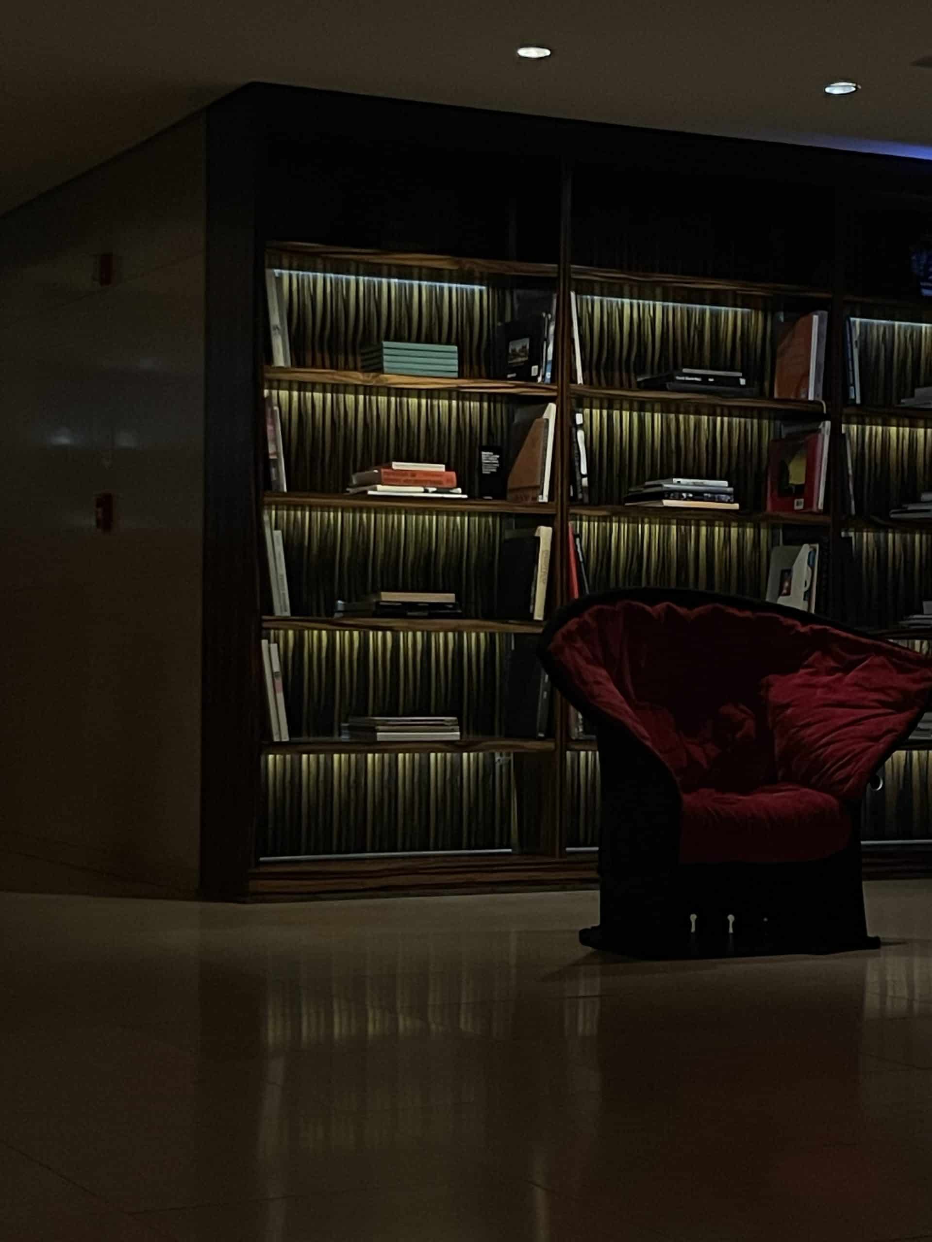 Hotel Unique São Paulo lobby with illuminated bookshelves and a red chair.