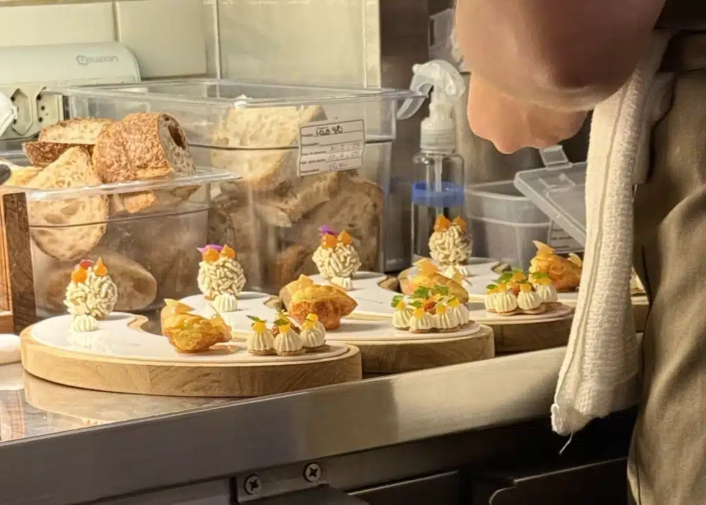 Nelita São Paulo Small bites arranged on serving boards as a cook works at the Nelita kitchen counter.