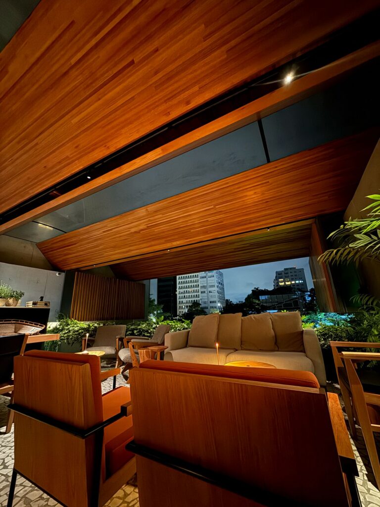 Tuju lounge with wooden beams, upholstered seating, greenery and city views.