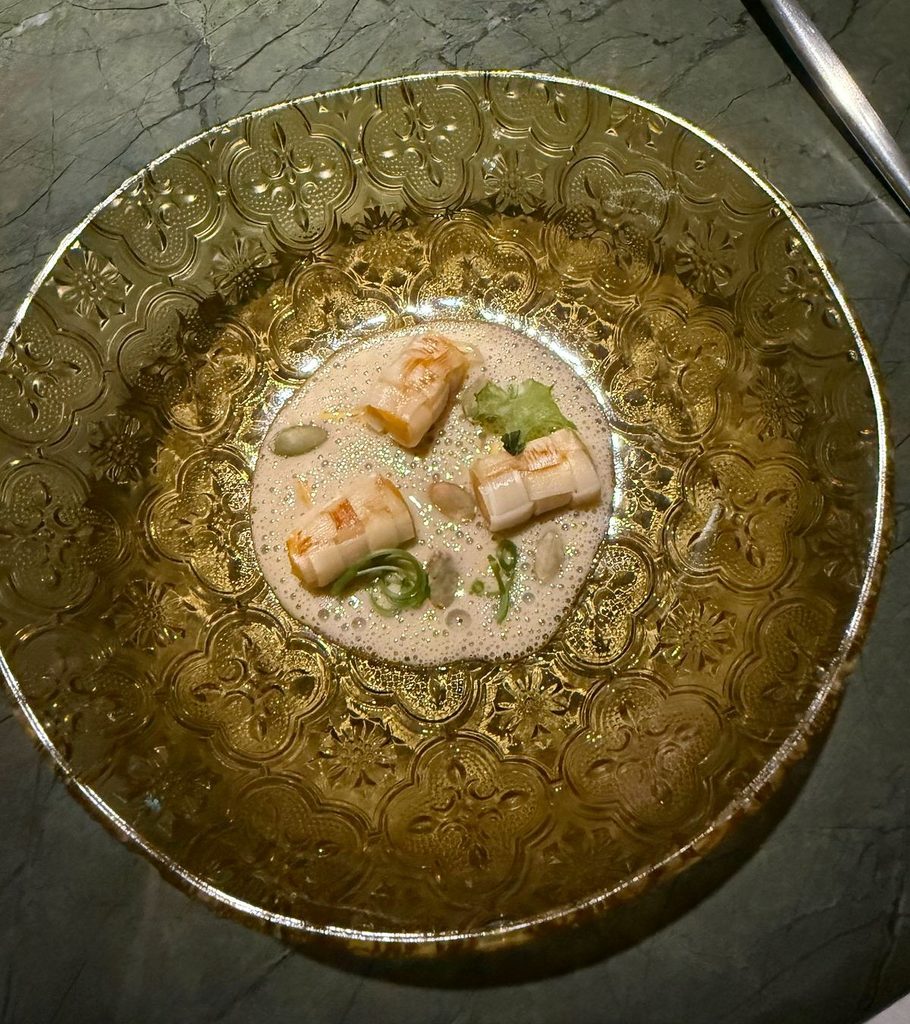 Exclusive Restaurants A plated course in an ornate gold-toned glass bowl on a green marble table at Tuju.