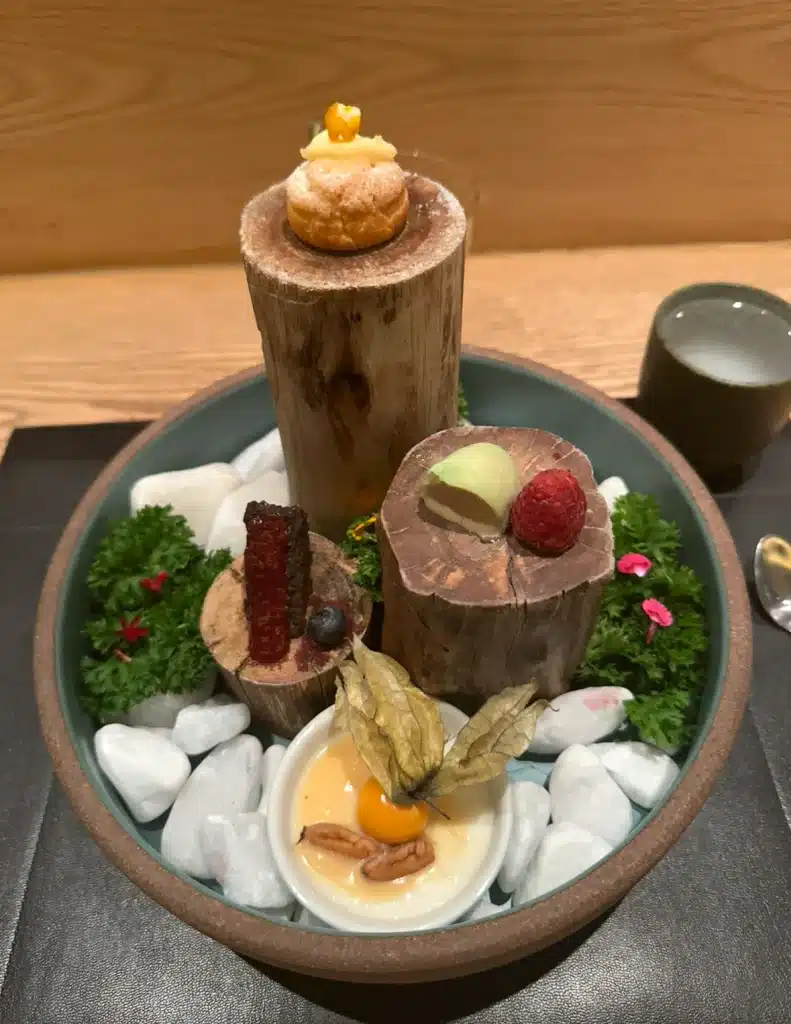FROM SUPERCARS TO SUITCASES Desserts arranged on wooden stands and white stones at Kazuo in São Paulo.