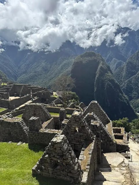 Stone ruins of Machu Picchu surrounded by cloud-covered mountains in Peru