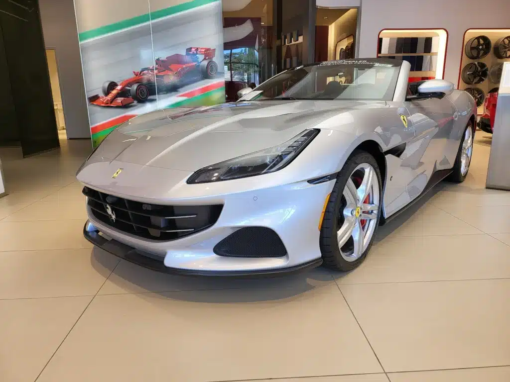 Richard Jarocki A silver Ferrari convertible inside a showroom, with a Formula 1 photograph on the wall behind it.