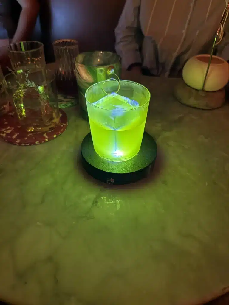 Travel Research A bright green cocktail illuminated from below on a table at Paradiso in Barcelona.