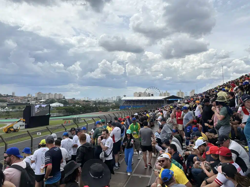 Richard Jarocki Spectators filling an open grandstand beside the Interlagos circuit under a cloudy sky.
