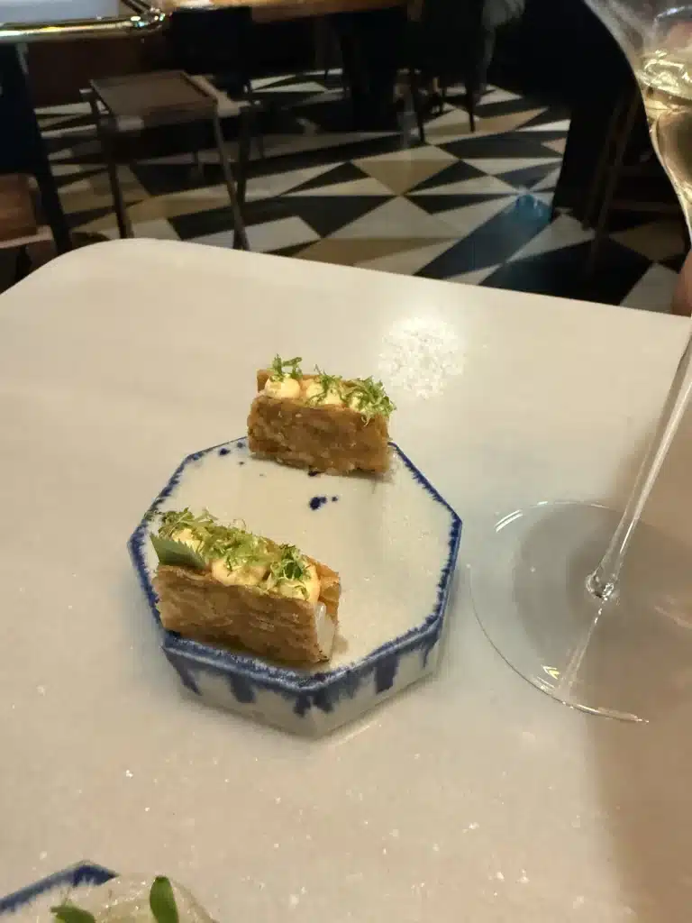 Travel Research Two rectangular small bites on a blue-edged ceramic plate at Mont Bar in Barcelona.