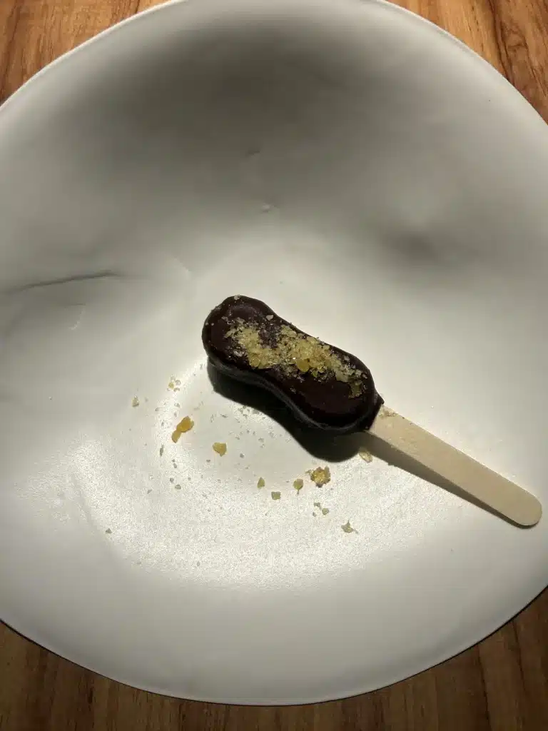 Pop Rocks ice cream bar on a stick, served on a white plate at Evvai.