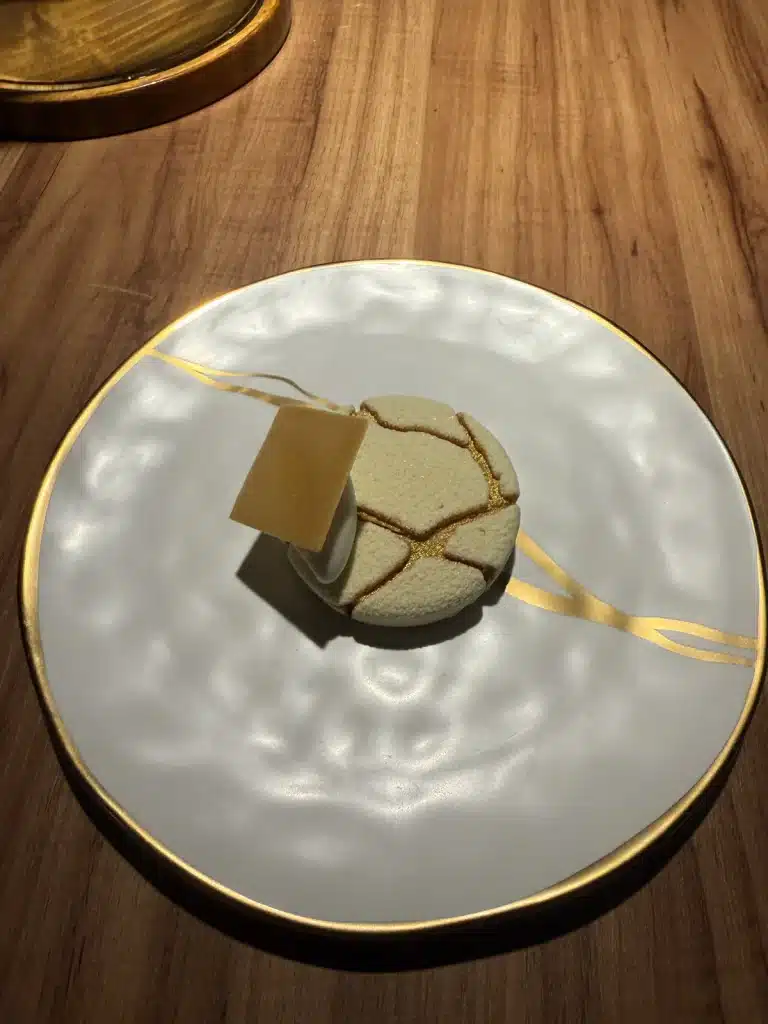 Round decorated dessert with a thin square garnish at Evvai in São Paulo