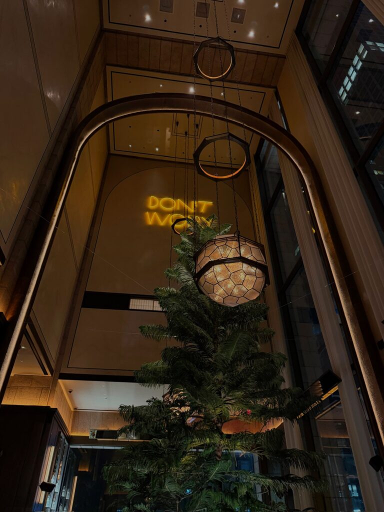 Interior of the Whiskey Bar at Bar Chimera inside 550 Madison in New York City, featuring soaring ceilings, contemporary lighting, and the illuminated "DON'T WORRY" installation.