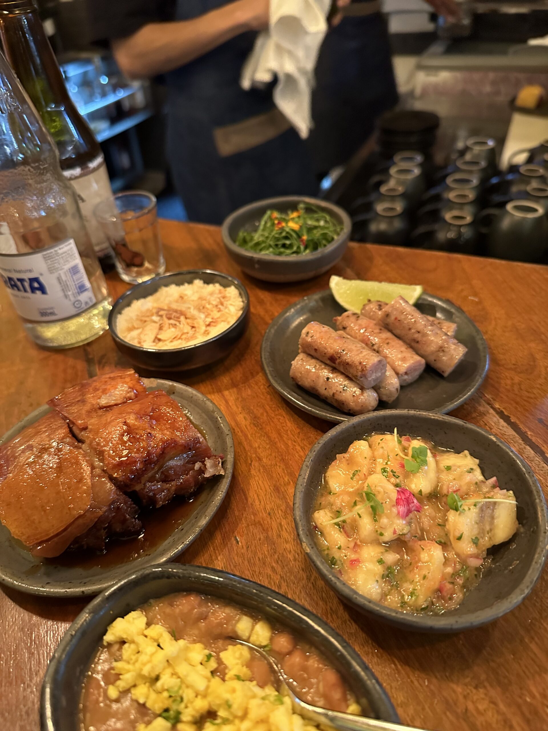 Selection of dishes from the tasting menu at A Casa do Porco in São Paulo, featuring roasted pork, house-made sausages, pork tartare, beans, and traditional Brazilian accompaniments.