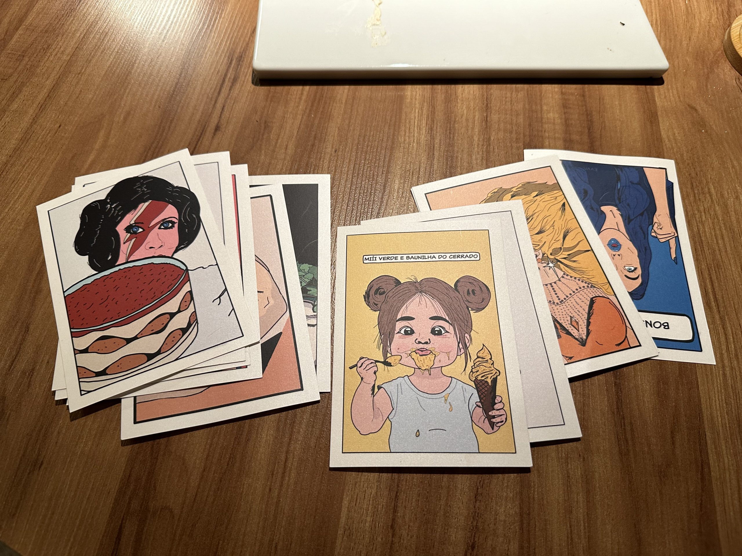 Collection of illustrated course cards received throughout the tasting menu at Evvai in São Paulo, featuring colorful pop-art artwork inspired by Brazilian culture and each individual course.