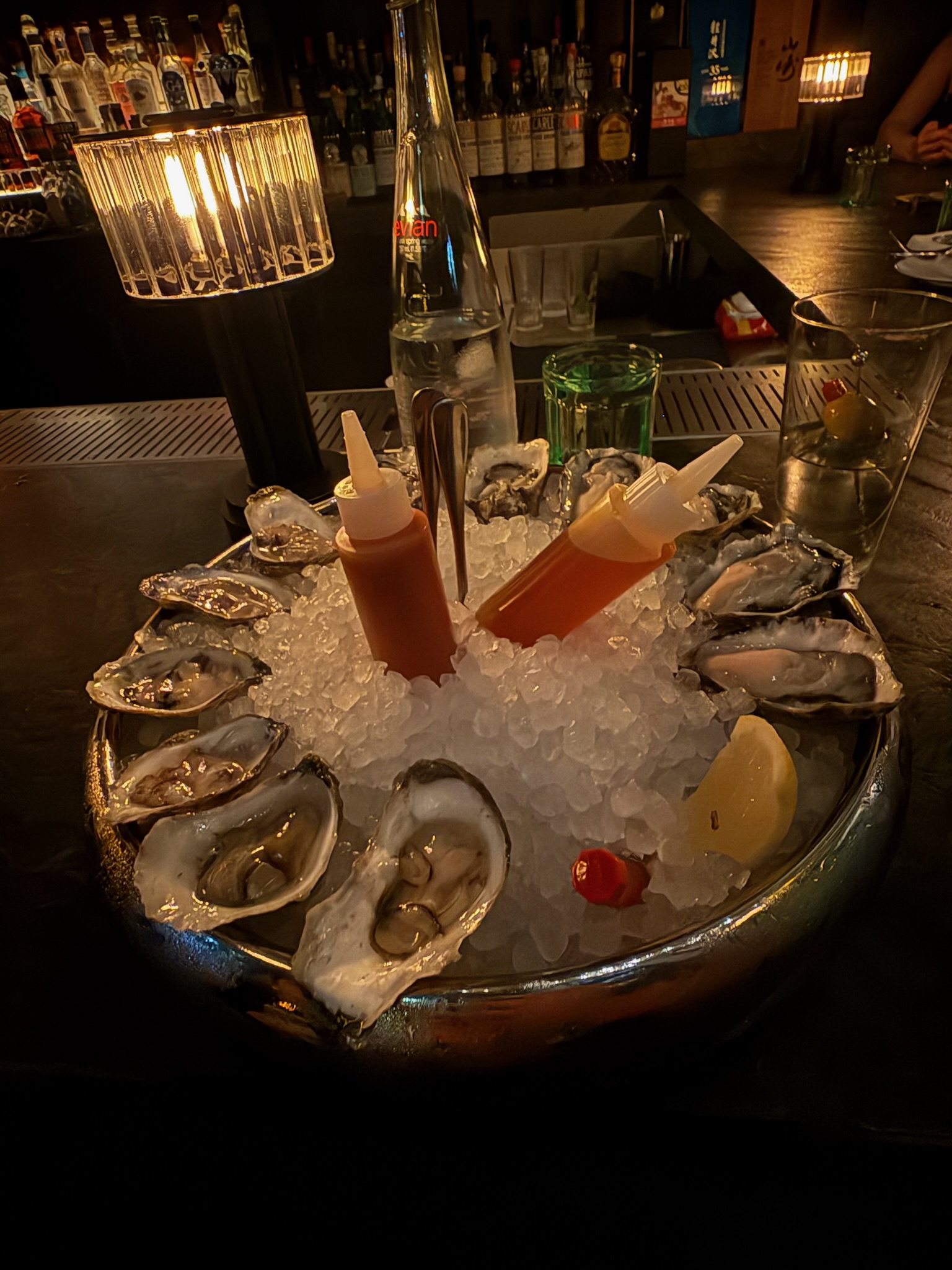 Food and Drink at Bar Chimera Fresh oysters served on crushed ice with cocktail sauce, mignonette, lemon, and cocktails at Bar Chimera in New York City.