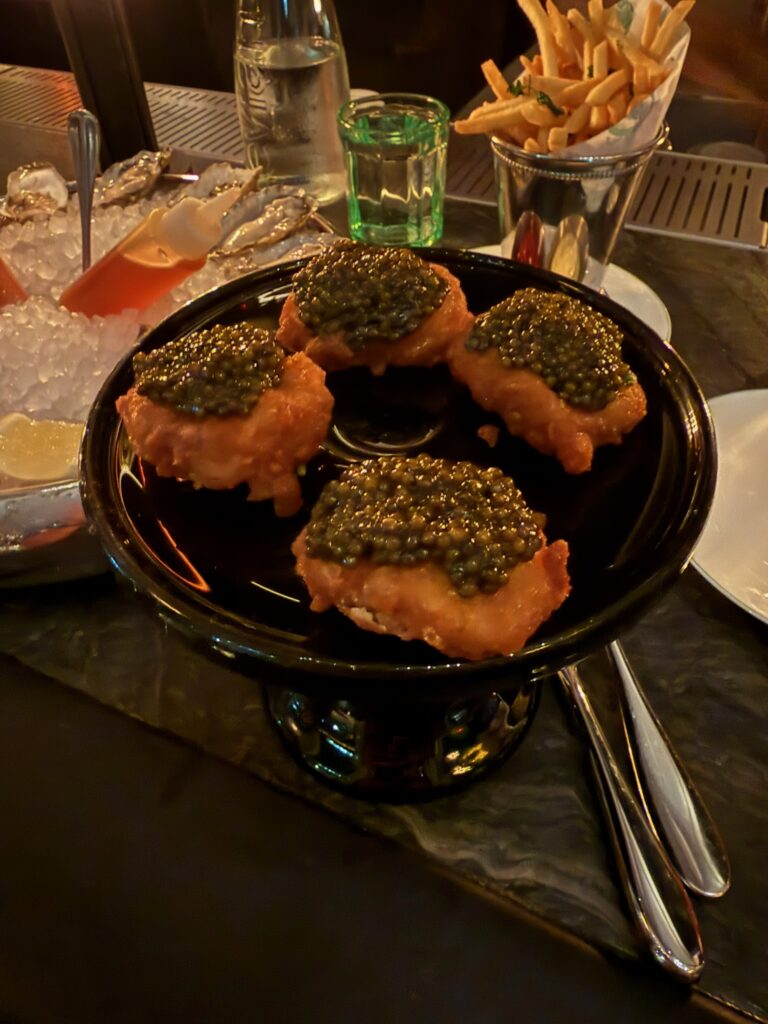 Bar Chimera's Golden Nuggets topped with premium caviar served alongside fresh oysters and tallow fries at 550 Madison in New York City.