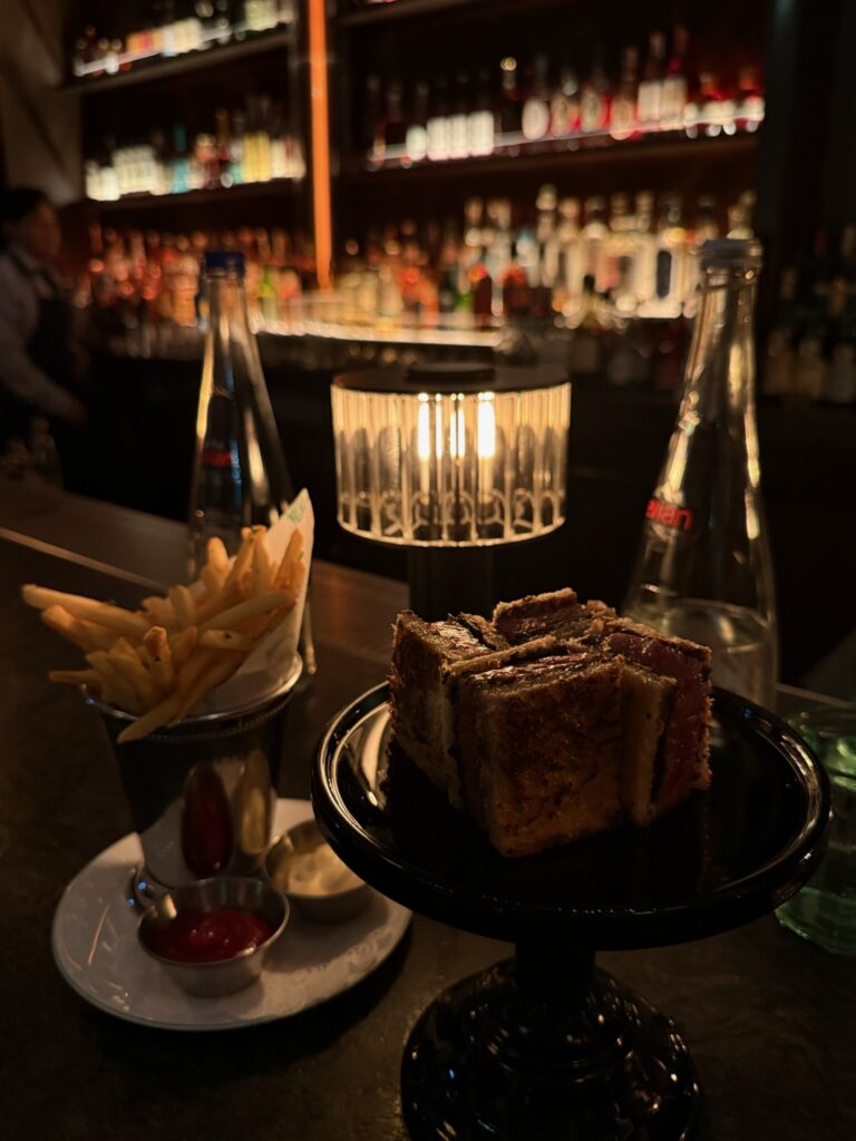 The A5 Blackjack Sandwich at Bar Chimera is cut into four pieces, revealing perfectly cooked Kagoshima A5 wagyu layered with Périgord black truffle and truffle aioli between buttery toasted milk bread. The sandwich is served at the restaurant's cocktail bar in New York City.