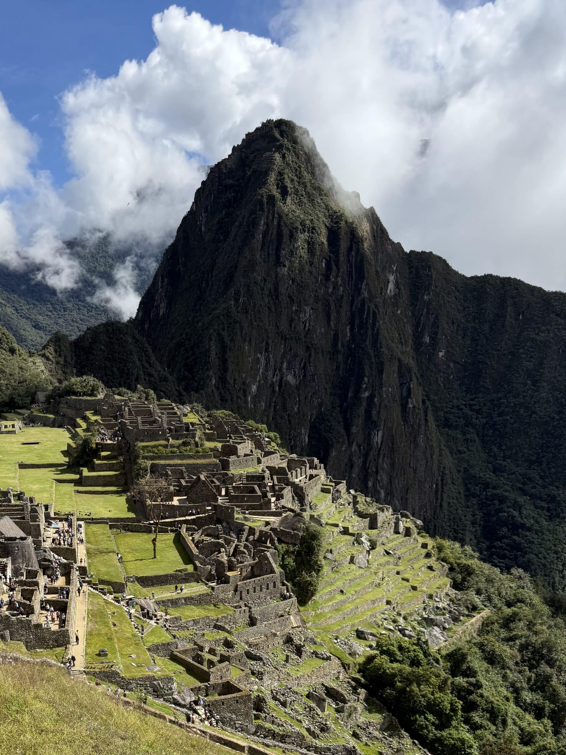 Panoramic view of Machu Picchu surrounded by green mountains and clouds in Peru