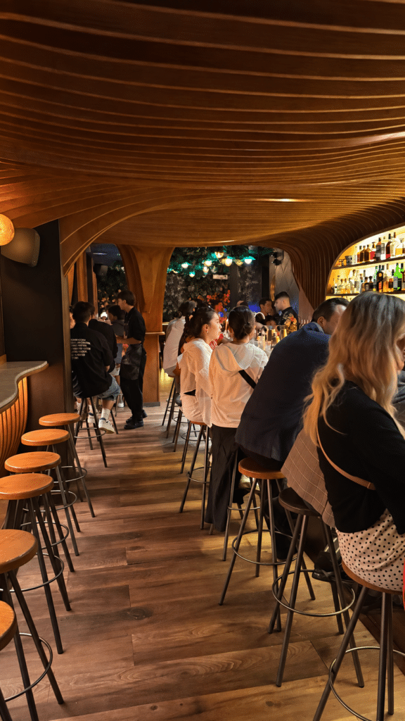 Formula 1 Guests seated beneath Paradiso’s curved wooden ceiling beside its illuminated cocktail bar.