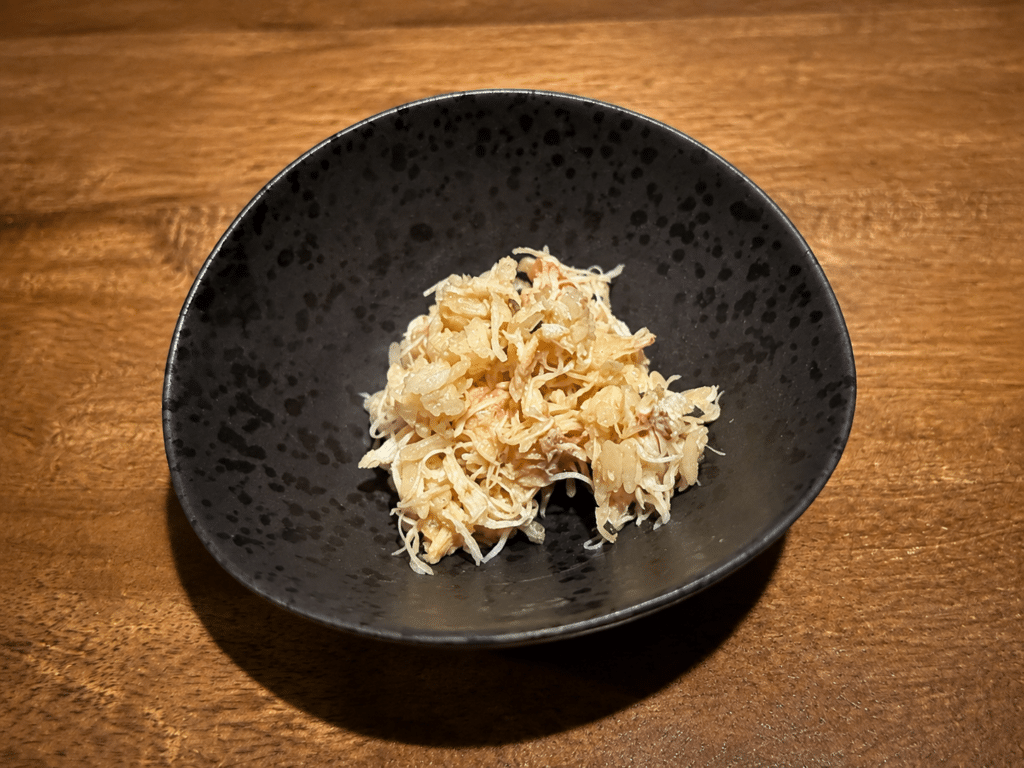 Prepared crab served in a small black bowl during the Dassai Blue omakase.