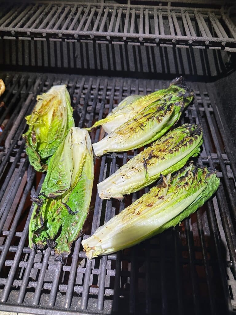 Romaine hearts with charred edges cooking on the grill