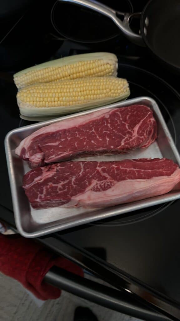New York strip steaks and fresh corn ready for the grill