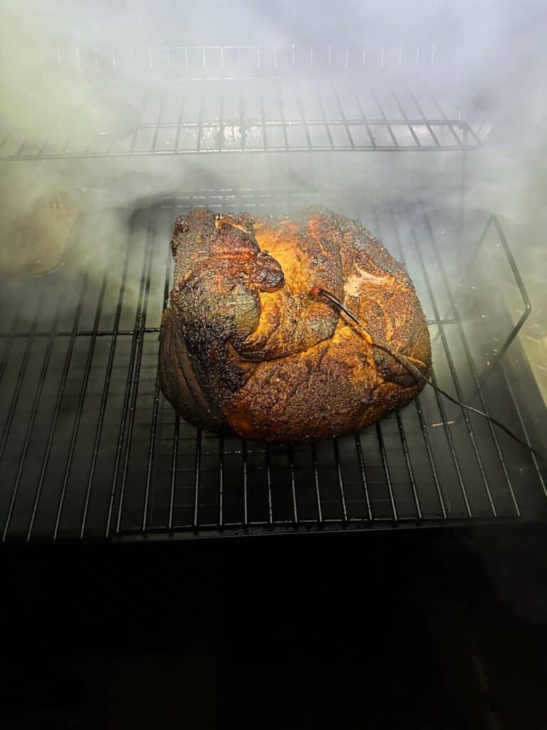 Smoked pork shoulder with dark bark and a temperature probe