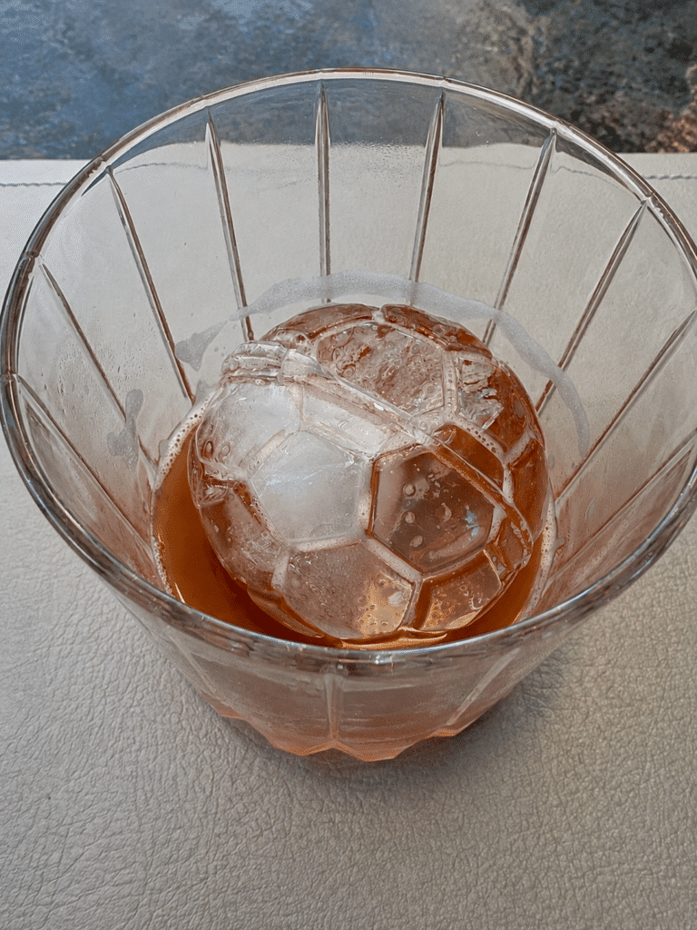 Close-up of soccer-ball-shaped ice inside the Halftime cocktail at the Blue Box Café in NYC