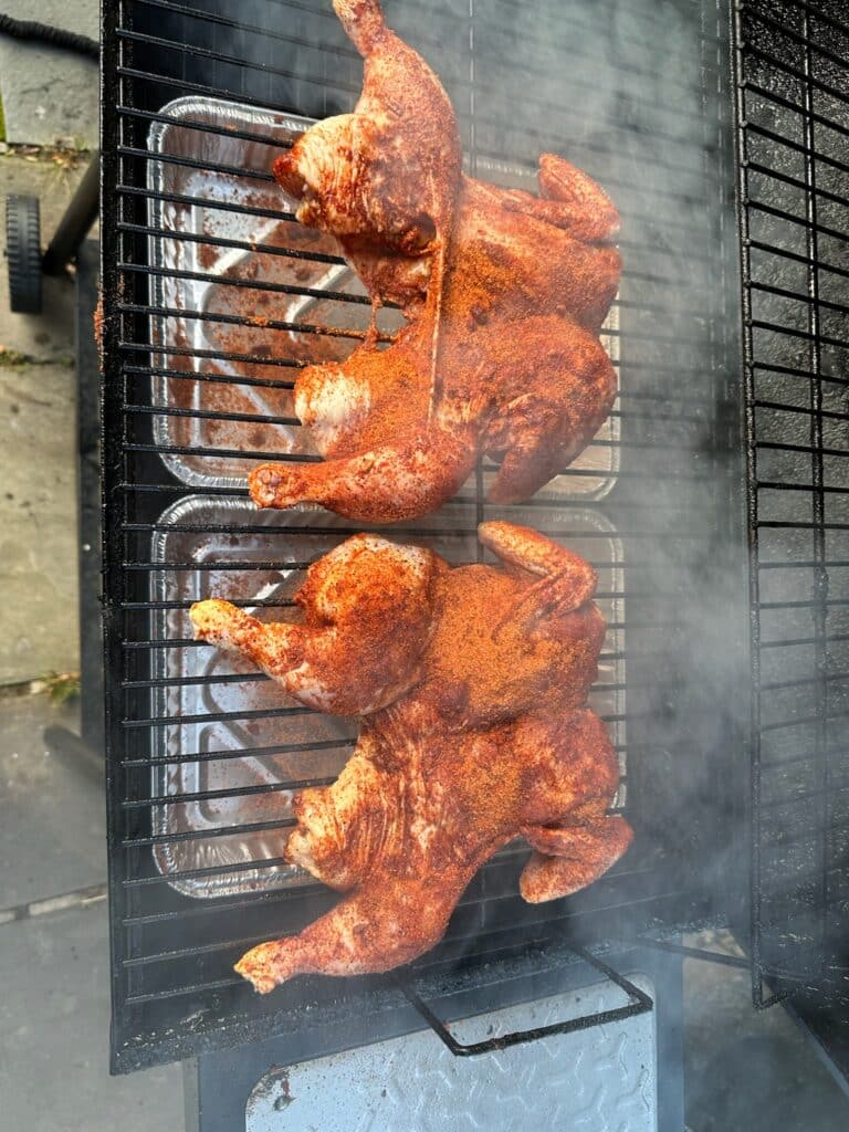Spice-rubbed chickens cooking on an outdoor smoker