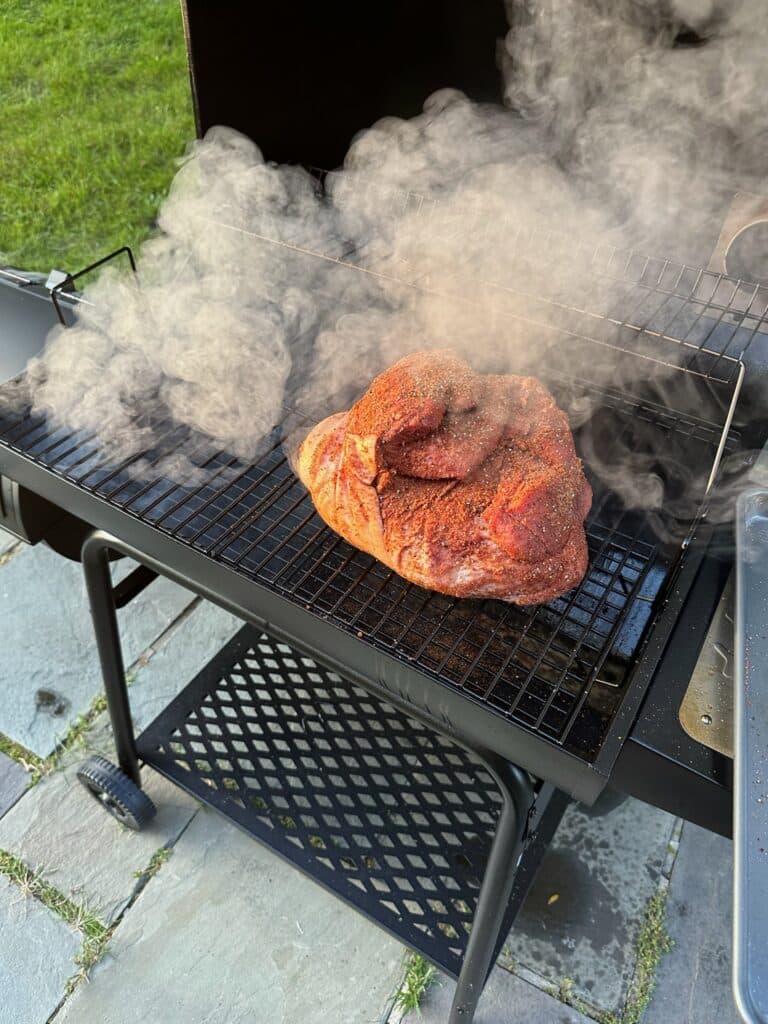 A seasoned pork shoulder at the start of a low-and-slow smoke