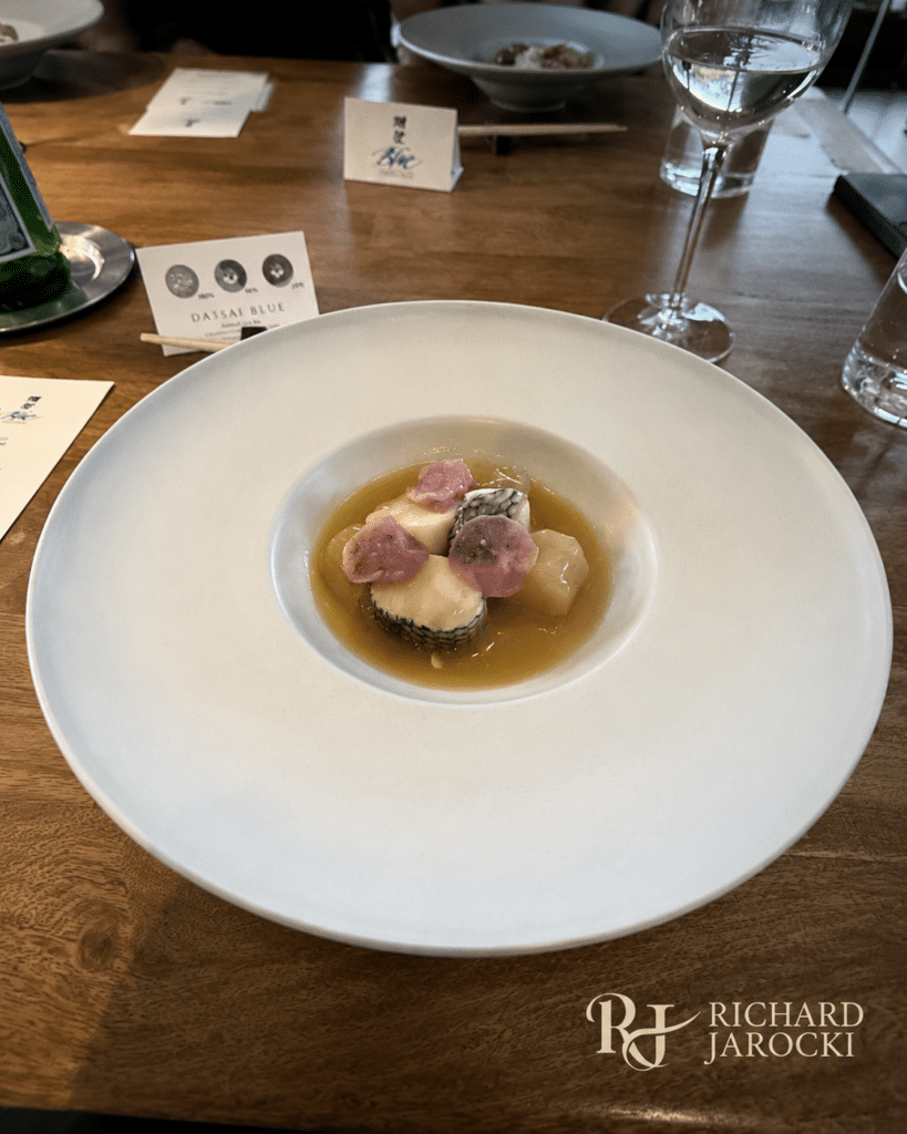 Poached black bass and scallop roulade served in a savory sake-kasu broth.
