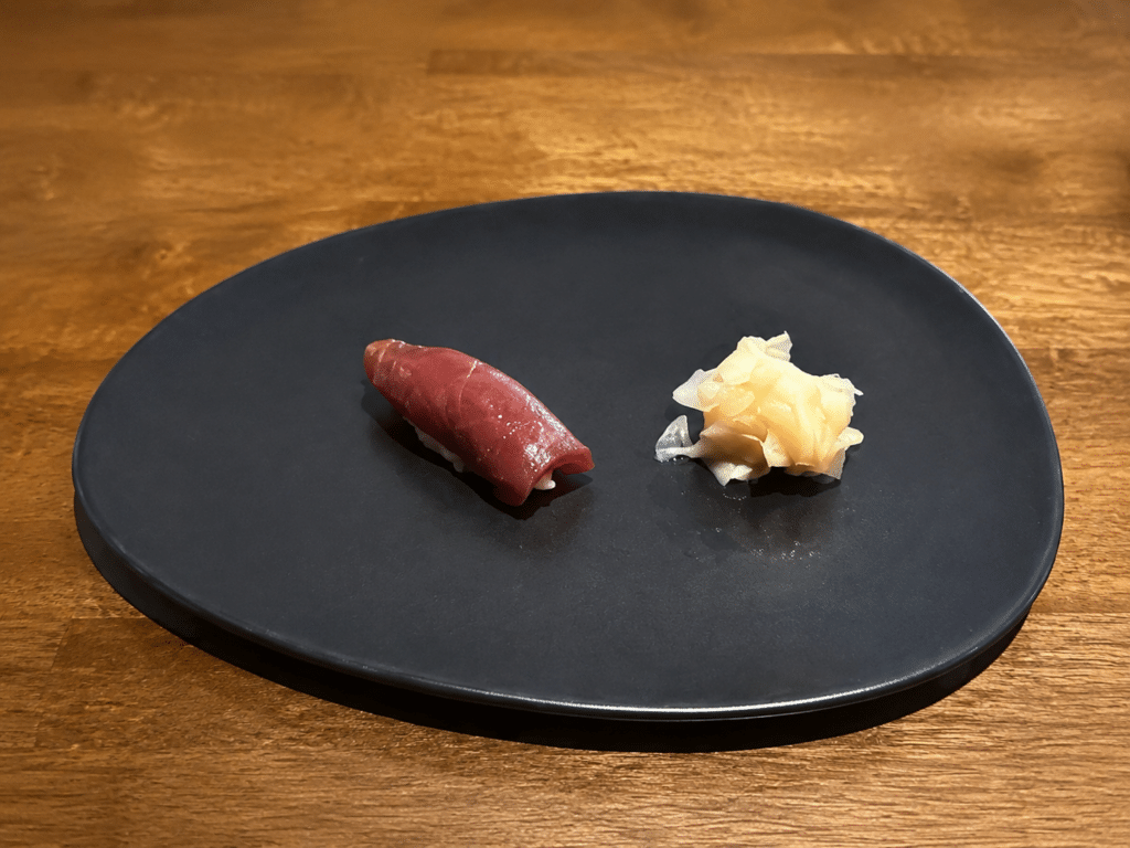 Lean bluefin tuna akami nigiri with pickled ginger on a black plate at Dassai Blue.