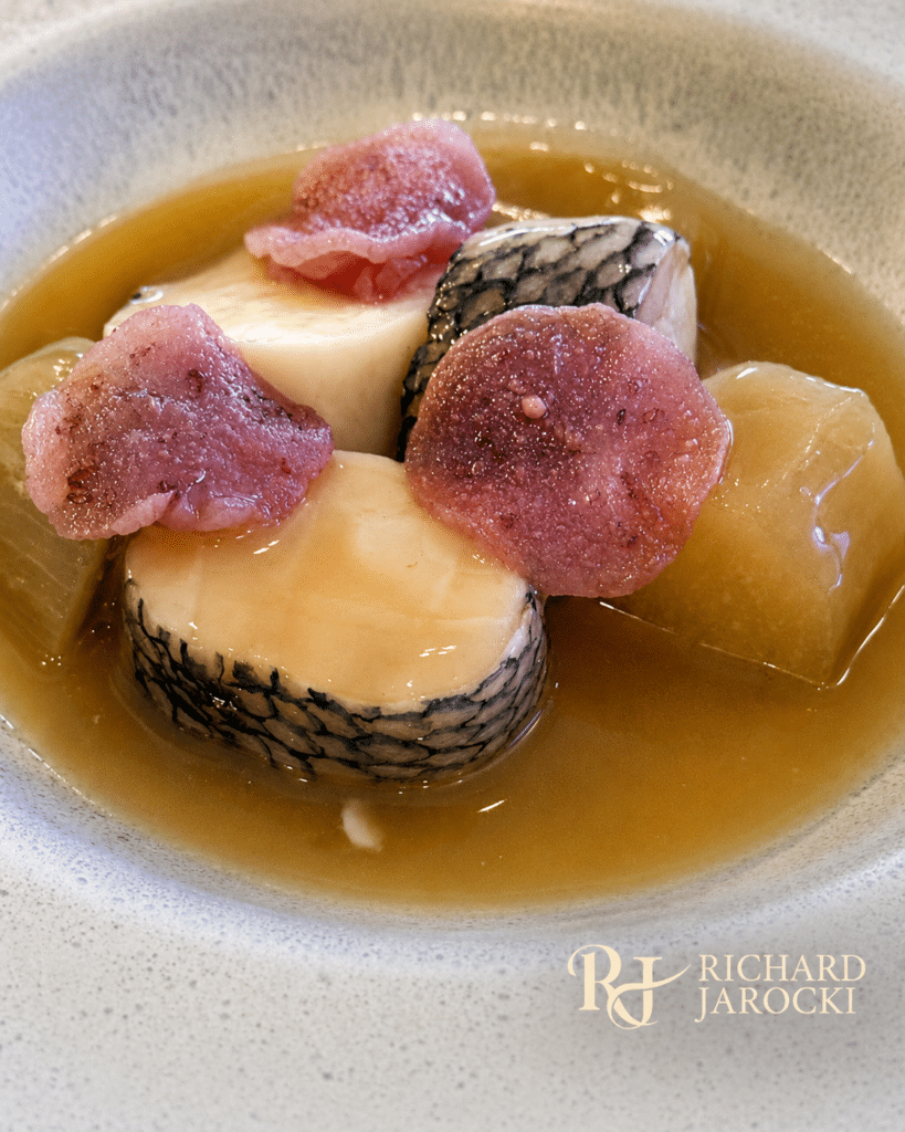 Black bass and scallop roulade with purple garnishes in sake-kasu broth.