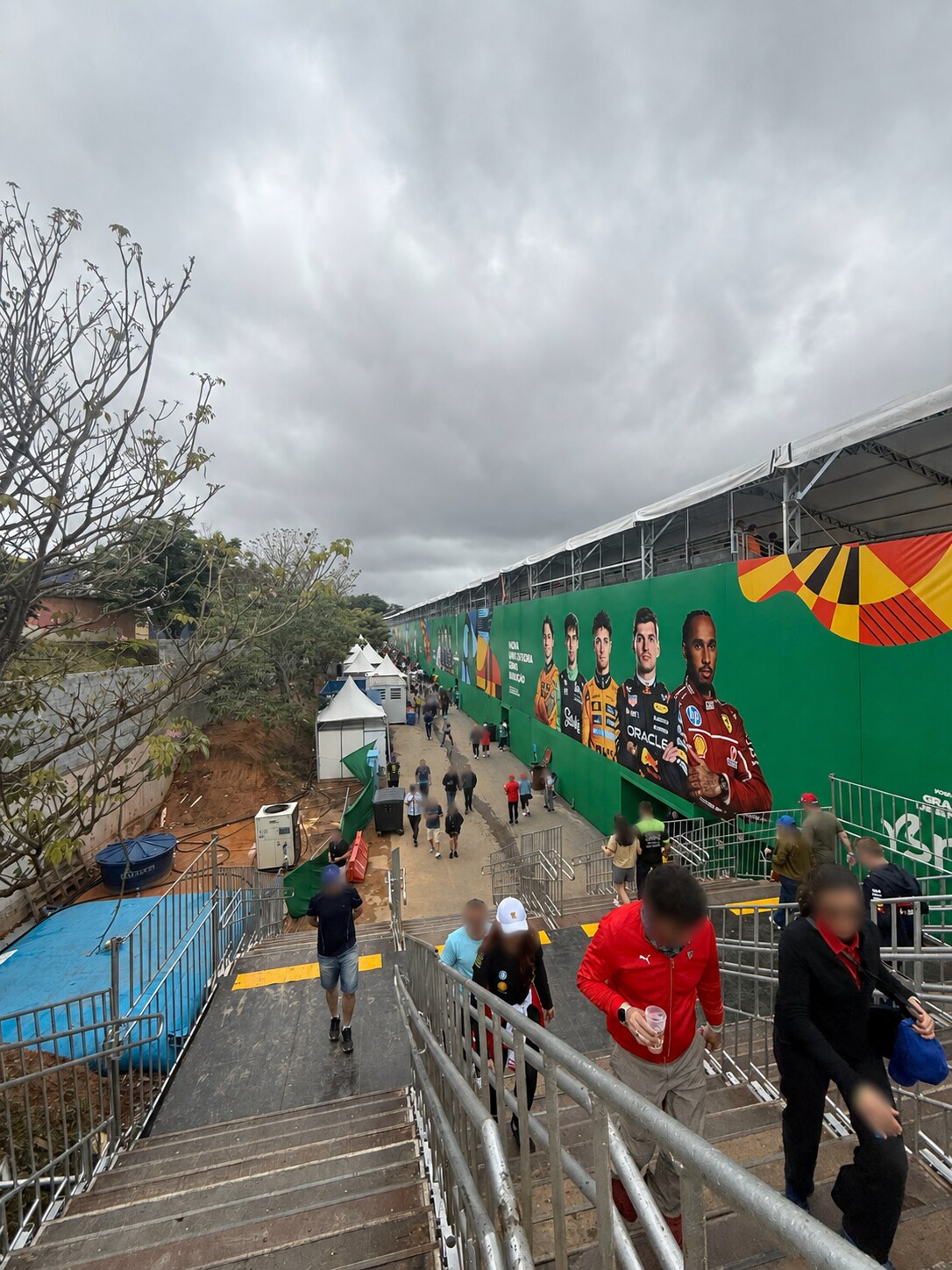 Fans walking beside a driver mural at Interlagos