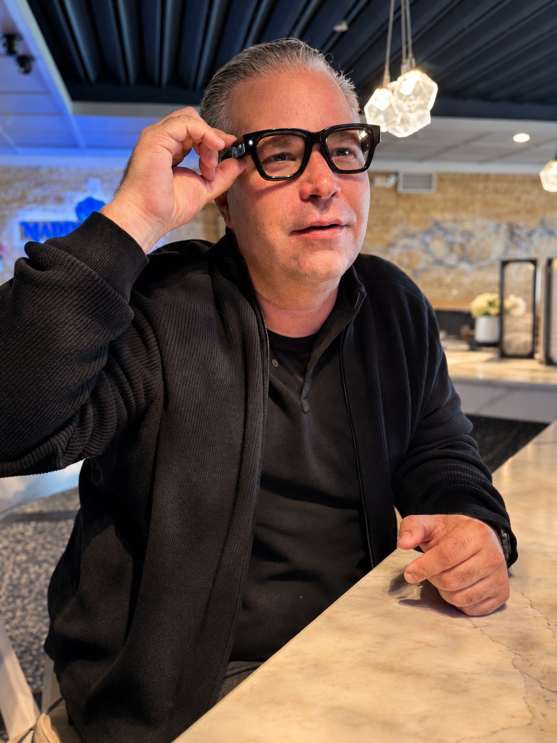 Richard Jarocki trying on Meta display glasses at a counter.