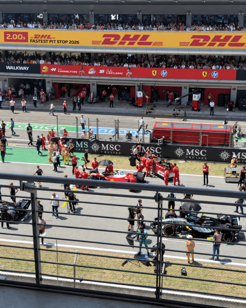 Why I Love Formula 1 A Ferrari Formula 1 car and team members on the Barcelona starting grid, with another team nearby.