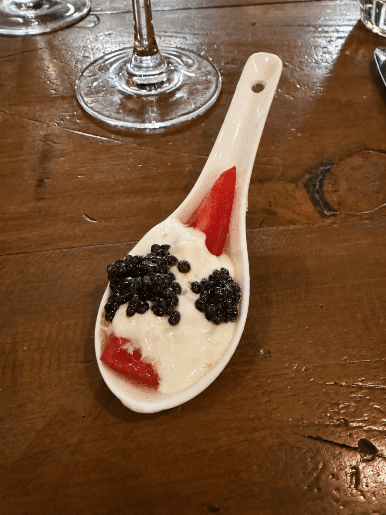Viaggio x La Valle Dinner Review NJ Tomato Bite Amuse-Bouche at Viaggio x La Valle Close-up of the NJ Tomato Bite amuse-bouche with whipped Meyer lemon ricotta and Altima caviar on a white ceramic spoon.